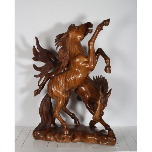 220 - A HARDWOOD CARVING modelled as two stallions one shown rearing raised on a naturalistic base 
103cm ... 