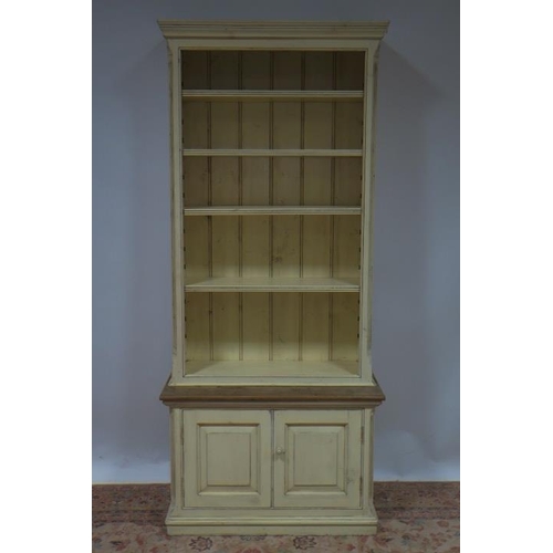 76 - A PINE AND CREAM PAINTED OPEN FRONT BOOKCASE the moulded cornice above five shelves, four adjustable... 