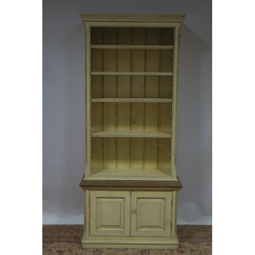 77 - A PINE AND CREAM PAINTED OPEN FRONT BOOKCASE the moulded cornice above five shelves, four adjustable... 