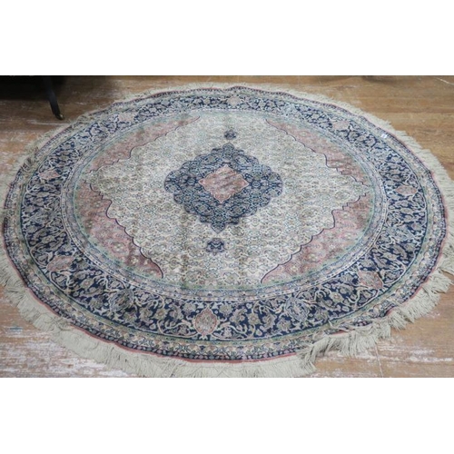 819 - A BEIGE, INDIGO AND LIGHT PINK GROUND RUG of circular outline the central panel filled with stylised... 