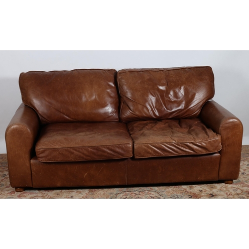 88 - A BROWN HIDE UPHOLSTERED TWO SEATER SETTEE with loose cushions and shaped arms on bun feet 
197cm (w... 