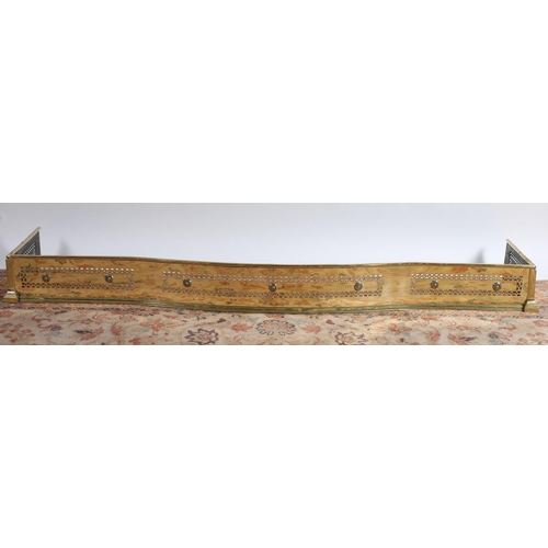 533 - A 19TH CENTURY BRASS FENDER of serpentine outline the cylindrical top rail above a pierced frieze wi... 