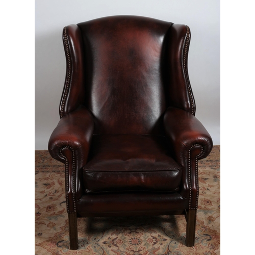 125 - A GEORGIAN DESIGN MAHOGANY AND UPHOLSTERED WING CHAIR with scroll over arms and loose cushion on squ... 