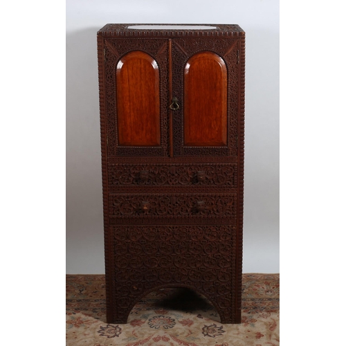 92 - A BURMESE CARVED HARDWOOD SIDE CABINET of rectangular outline the shaped top with arched panel doors... 