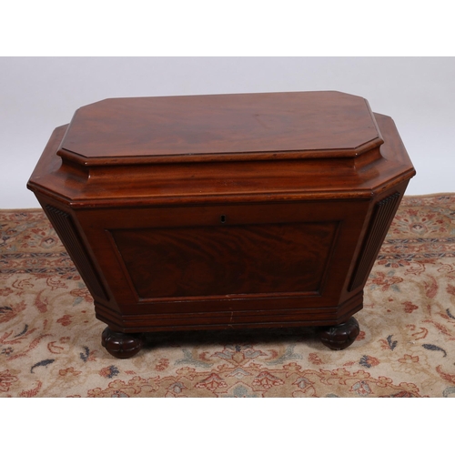 74 - A 19TH CENTURY MAHOGANY CELLARETTE of sarcophagus outline the stepped hinged lid above a panelled fr... 