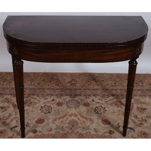 87 - A GEORGIAN MAHOGANY FOLD OVER CARD TABLE of demi lune outline the hinged top containing a baize line... 