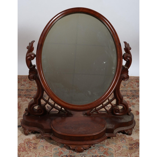 94 - A 19TH CENTURY MAHOGANY CRUTCH FRAME MIRROR the oval plate within a moulded frame raised on a carved... 