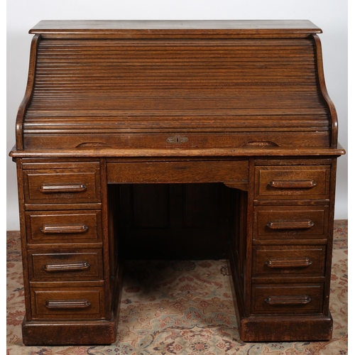 521 - A VINTAGE OAK ROLL TOP DESK the rectangular top above a tambour shutter containing pigeon holes and ... 