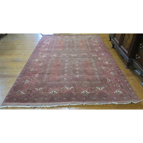 543 - AN ORIENTAL WOOL RUG the wine ground with central panel filled with palmets, stylised flowerheads an... 