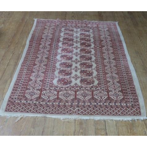 549 - AN ORIENTAL WOOL RUG the beige ground with central panel filled with serrated hooks, palmets and sty... 