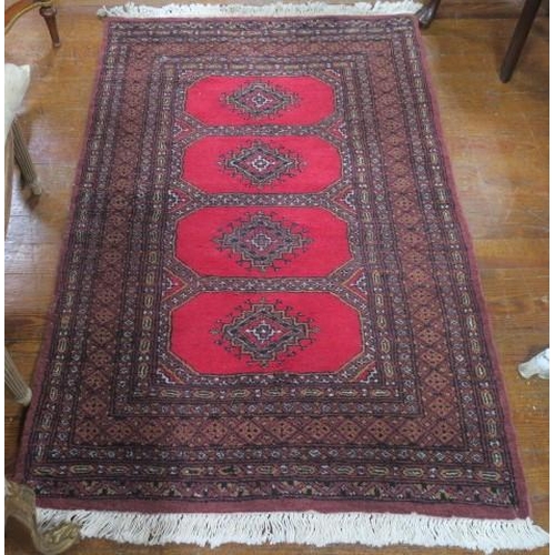 557 - A BOKHARA WOOL RUG the wine, light pink and light brown ground with central panels filled with palme... 