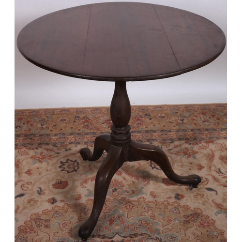 702 - A GEORGIAN MAHOGANY OCCASIONAL TABLE of circular outline, the shaped top above baluster column on tr... 