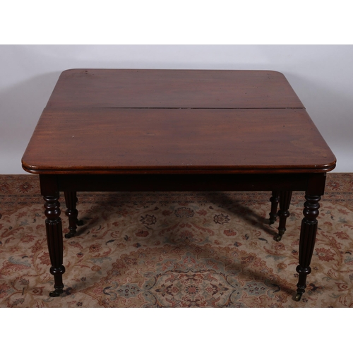 715 - A GEORGIAN MAHOGANY DINING TABLE of rectangular outline with rounded corners and reeded rim raised o... 