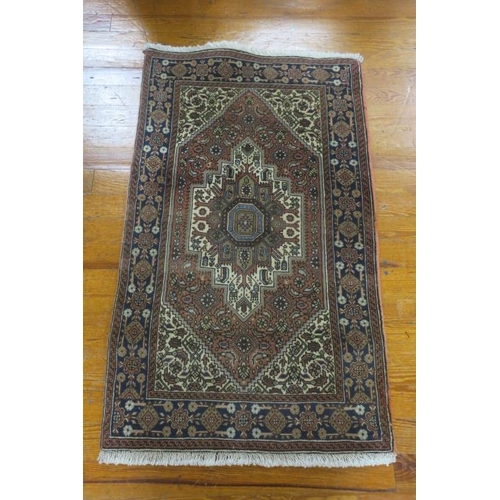 734 - AN ORIENTAL WOOL RUG the light brown ground with central panel filled with stylised flowerheads and ... 