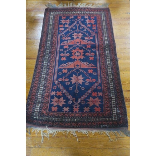 735 - AN ORIENTAL WOOL RUG the indigo and wine ground with central panel filled with serrated panels with ... 