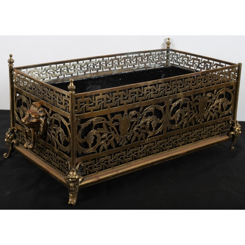 911 - A 19TH CENTURY PIERCED BRASS PLANTER of rectangular outline with lion mask handles raised on figural... 