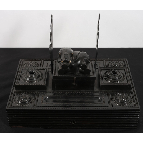 122 - A CARVED EBONY DESK STAND of rectangular outline fitted with ink wells, pen compartments and pen res... 