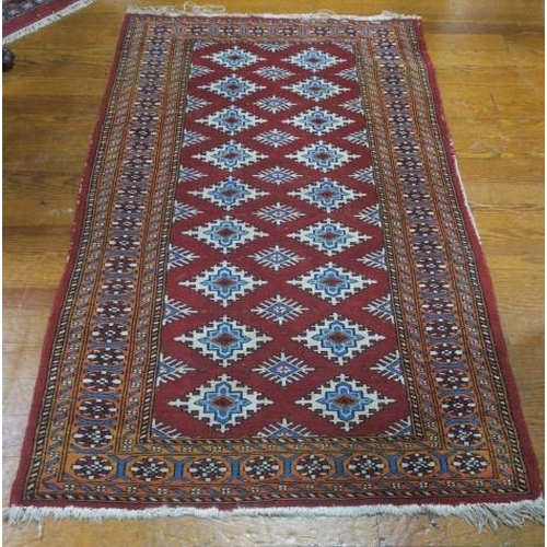 550 - AN ORIENTAL WOOL RUG the wine ground with central panel filled with serrated panels within a conform... 