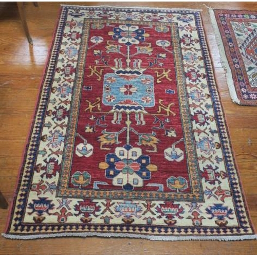 552 - AN ORIENTAL WOOL RUG the wine ground with central panel filled with stylised flowerheads and foliage... 