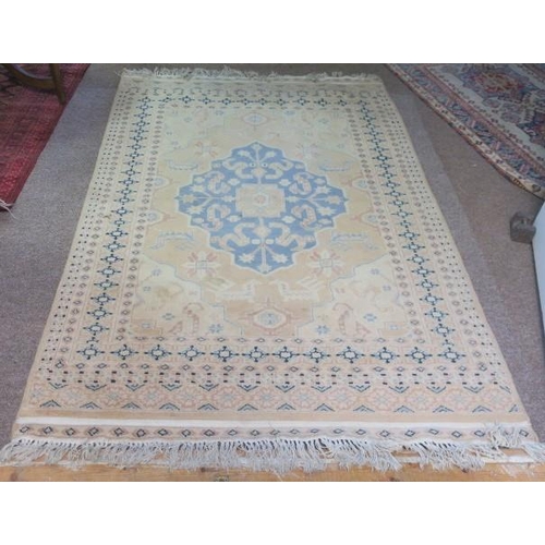 556 - A WOOL RUG the light pink and beige ground with central panel filled with stylised flowerheads and f... 