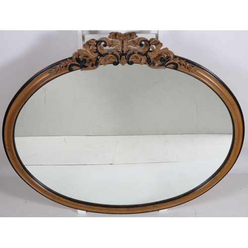 660 - AN ITALIAN SIMULATED CARVED WOOD AND EBONISED MIRROR of oval outline the shaped plate within a mould... 