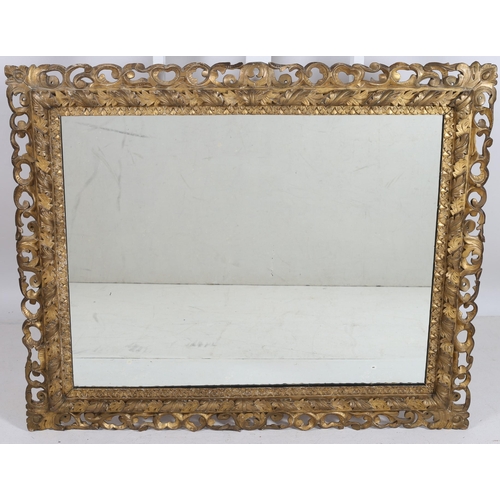 748 - A CONTINENTAL GILT FRAME MIRROR the rectangular plate within a foliate flowerhead and pierced C-scro... 