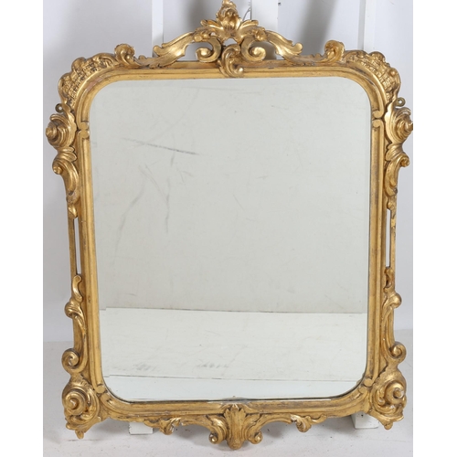 755 - A VINTAGE CONTINENTAL CARVED GILTWOOD AND GESSO MIRROR the bevelled glass plate within a foliate scr... 