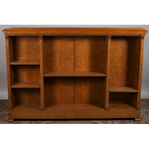 87 - A REGENCY SATINWOOD OPENFRONT BOOKCASE of rectangular outline the shaped top with scroll frieze abov... 