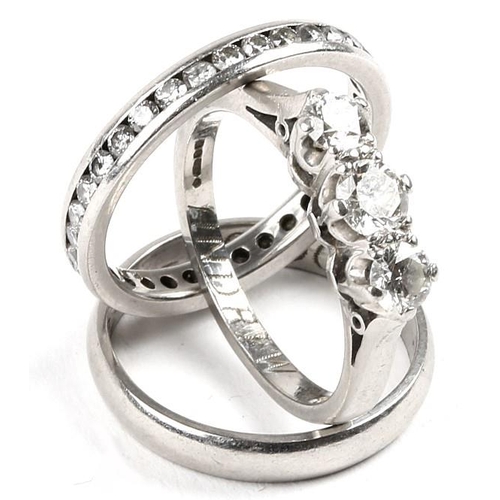 501 - A TRIO WEDDING SET, a platinum wedding band , a platinum and diamond eternity ring, a three stone  p... 