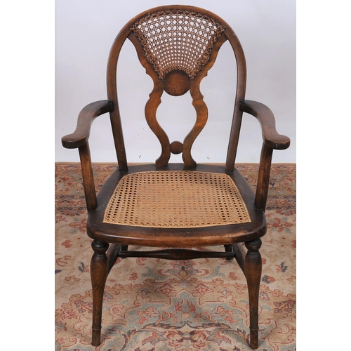 51 - A VINTAGE STAINED WOOD AND CANED ELBOW CHAIR the shaped back above a cane seat on moulded legs