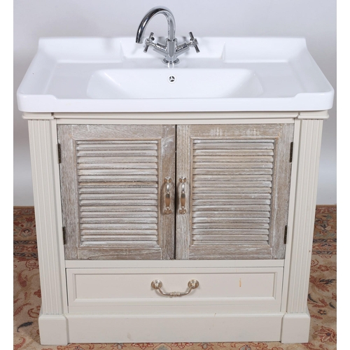 13 - A VINTAGE GREY PAINTED VANITY UNIT with porcelain wash basin and chrome taps above a pair of louvre ... 