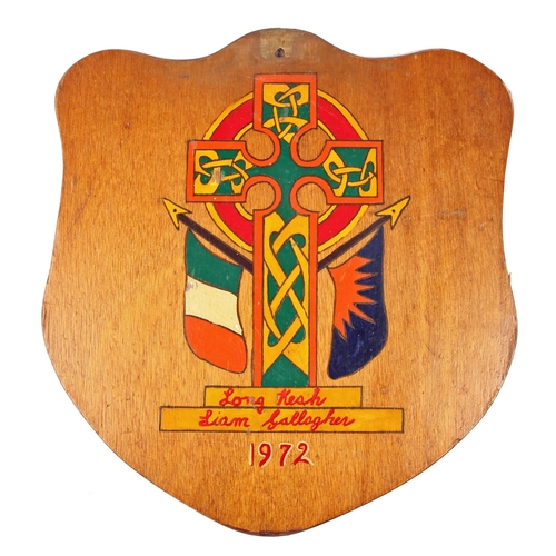 91 - Prisoner Art, Long Kesh 1972, a shield shaped wooden panel painted with a Celtic Cross flanked by an... 