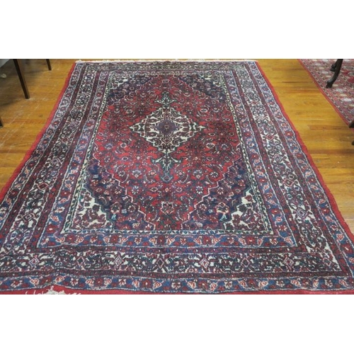 171 - A KESHAN WOOL RUG the wine, indigo and wine ground with central panel filled with stylised flowerhea... 