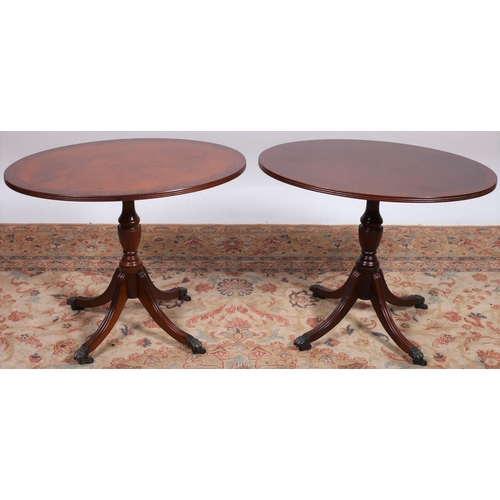 221 - A PAIR OF REGENCY DESIGN MAHOGANY CROSSBANDED TABLES each of oval outline the reeded rim above a bal... 