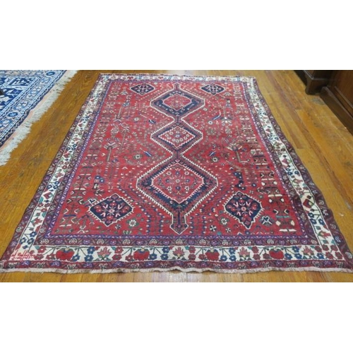 398 - AN ORIENTAL WOOL RUG the wine and indigo ground with central panel filled with stylised flowerheads ... 