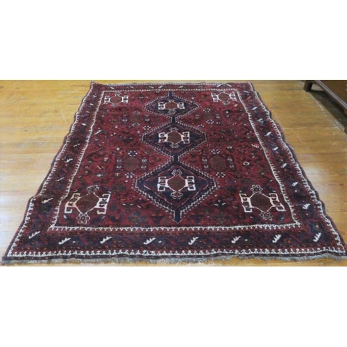 400 - AN ORIENTAL WOOL RUG the wine ground with central panel filled with stylised flowerheads and foliage... 