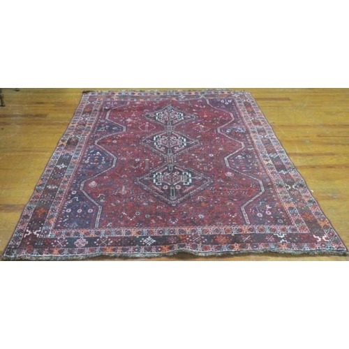 404 - AN ORIENTAL WOOL RUG the wine ground with central panel filled with stylised flowerheads and foliage... 