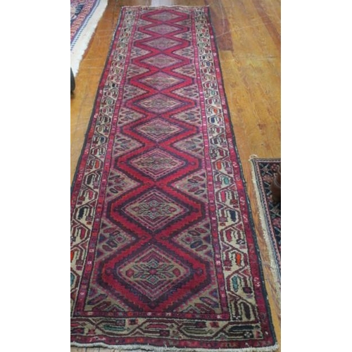 552 - A HAMADAN WOOL RUNNER the red ground with central diamond shaped panels within a conforming border 
... 