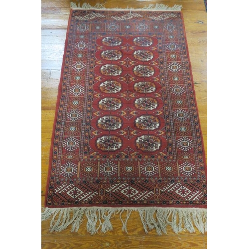 807 - AN ORIENTAL WOOL RUG the wine ground with central panel filled with octagonal shaped panels, palmets... 