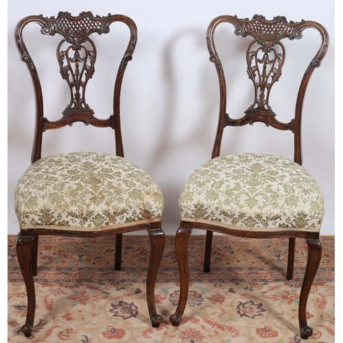 628 - A PAIR OF EDWARDIAN CARVED MAHOGANY SIDE CHAIRS each with a pierced C-scroll top rail with pierced s... 