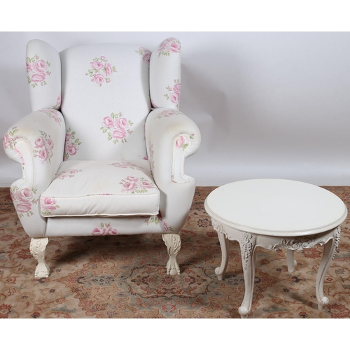 680 - A WHITE AND PINK FLORAL UPHOLSTERED WING CHAIR with scroll over arms and loose cushion on cabriole l... 