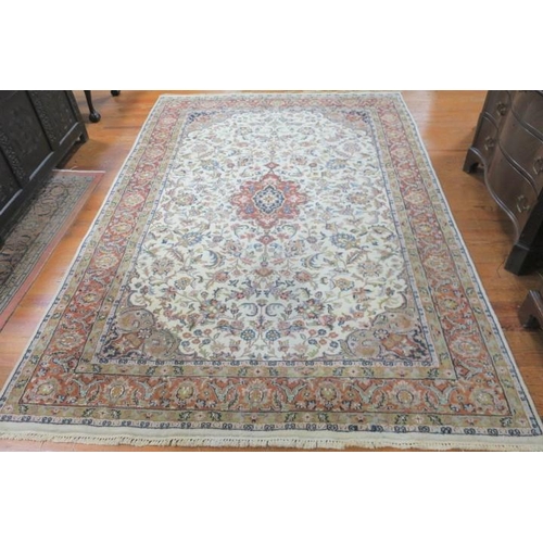 167 - A QUM WOOL RUG the beige and light green ground the central panel filled with flowers and foliate wi... 