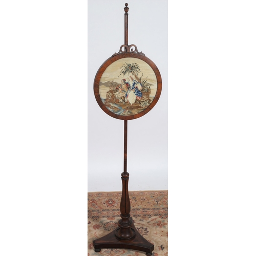 31 - A 19TH CENTURY ROSEWOOD FIRE SCREEN the oval needlework panel depicting figures shown seated above a... 