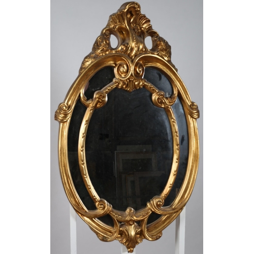 317 - A CONTINENTAL GILT FRAME COMPARTMENTED MIRROR the oval plate within a moulded frame with foliate cre... 