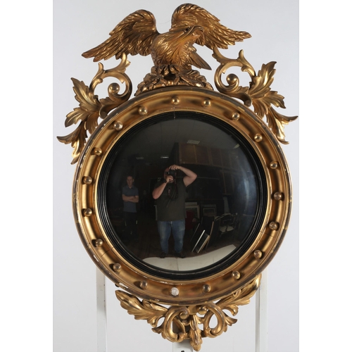 352 - A 19TH CENTURY GILTWOOD AND GESSO CONVEX MIRROR the ball decorated frame with eagle and pierced foli... 