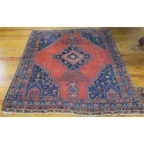 406 - AN ORIENTAL WOOL RUG the wine and indigo ground with central panel filled with serrated diamond shap... 