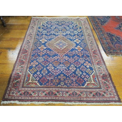 408 - AN ORIENTAL WOOL RUG the indigo and wine ground with central panel filled with stylised flowerheads ... 