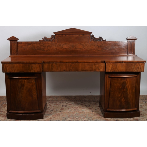 463 - A 19TH CENTURY MAHOGANY PEDESTAL SIDEBOARD of inverted breakfront outline the shaped top with a carv... 