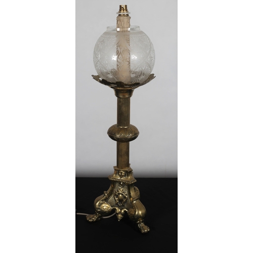 563 - A GILT BRASS TABLE LAMP the etched glass globe shade above a reeded and knopped column on triform ba... 