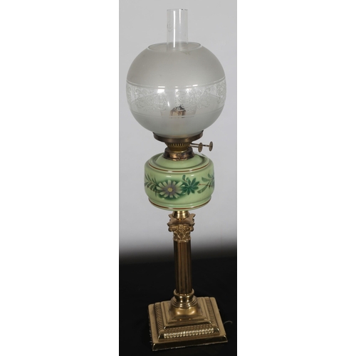 564 - A VINTAGE BRASS AND PORCELAIN OIL LAMP the etched and frosted glass shade above a green glass reserv... 